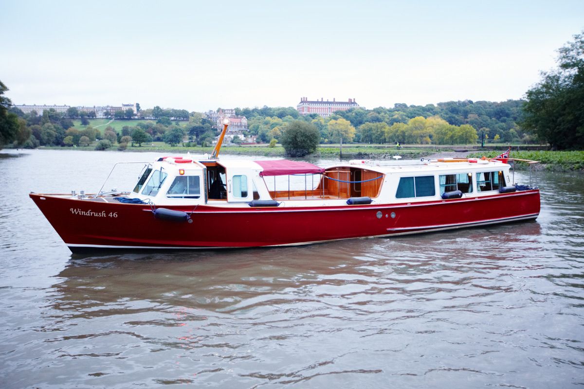 The Windrush, a classic red-hulled private yacht, cruising the River Thames